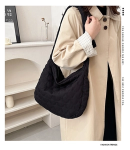 Detail of black wave-quilted hobo bag showing the rich stitching texture and crescent shape