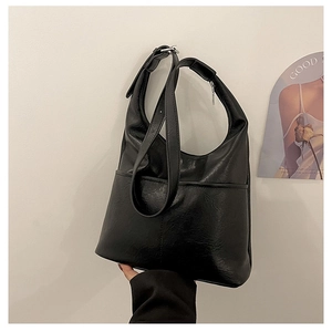 Détail de la texture cuir synthétique noir sur un sac porté épaule hobo minimaliste