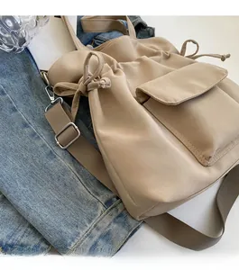 Detail of canvas bucket bag showing drawstring closure and adjustable woven shoulder strap