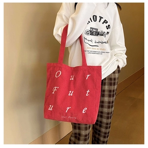 Detail of burgundy corduroy tote bag featuring white Our Future script embroidery
