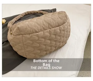 Detailed close-up of quilted beige tote bag bottom with textured stitching and golden zipper