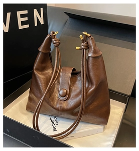 Detail of dark brown leather tote bag showing fine oily texture and knot strap