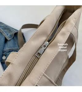 Detail of smooth metal zipper on a beige canvas tote bag with textured fabric detail
