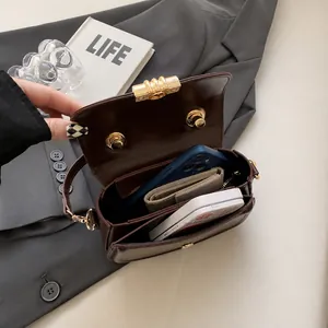 Detail showing the spacious interior of a dark brown saddle bag with golden lock