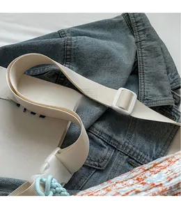 Close-up of adjustable cream woven strap with high-quality buckles on a casual bag