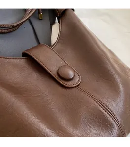 Close-up of dark brown leather tote bag showing fine stitching and soft texture
