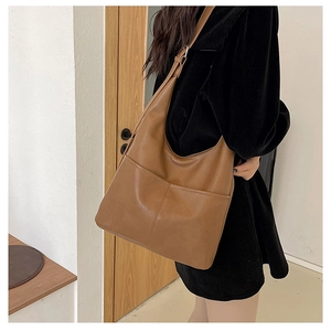 Vue détaillée d'un grand sac hobo marron montrant sa texture vintage et sa poche frontale