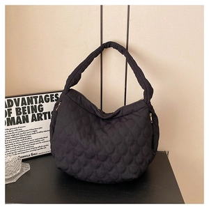 Detail of black quilted canvas tote bag showing fish-scale texture and wide shoulder strap