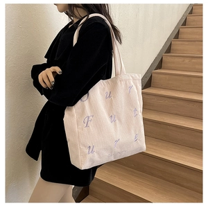 Detail of light beige corduroy tote bag with purple 'FUTURE' embroidery on stairs