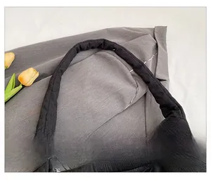 Close-up of padded quilted shoulder strap on black tote bag with premium textured fabric