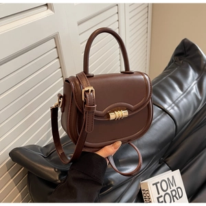 Detail of dark brown saddle bag featuring golden multi-ring lock and smooth leather texture