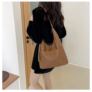 Grand sac seau en cuir marron avec large bandoulière et coutures verticales décoratives