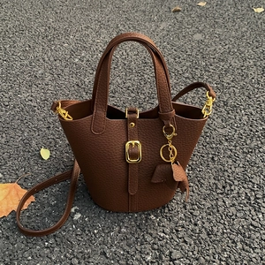 Braune Eimer-Handtasche aus Litschi-Leder mit goldener Schnalle und Elefantenanhänger