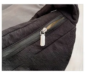Detailed close-up of the smooth metal zipper and quilted texture on the black tote bag