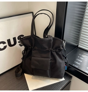Detailed macro of black canvas drawstring bucket bag with flap pocket and contrast label
