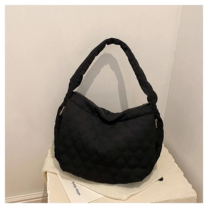 Detailed close-up of black quilted bubble texture and gold zipper on canvas tote bag