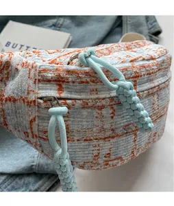 Detail view of plaid corduroy fanny pack showing dual zippers and braided rope pulls