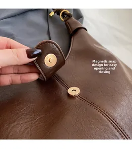 Detail of dark brown leather tote bag featuring a gold magnetic closure buckle and stitching