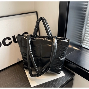 Nahaufnahme einer schwarzen gesteppten Puffer-Tasche mit glänzender Nylon-Textur und Nähten