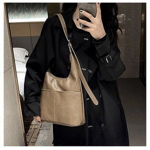 Selfie miroir montrant le sac hobo en cuir marron porté sur un trench-coat noir