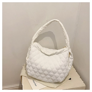 Detailed close-up of white heart-quilted canvas tote bag on a textured stone display