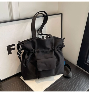 Close-up of black drawstring tote bag with functional flap pocket and canvas texture