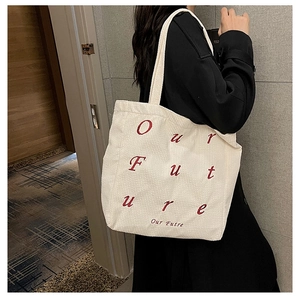 Detail of off-white corduroy tote bag with red 'Our Future' embroidery on the side