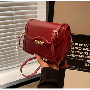 Detail of red crossbody saddle bag with gold hardware and smooth leather finish