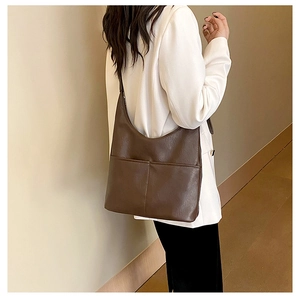 Sac hobo marron en similicuir avec poches avant porté par un mannequin, style épuré
