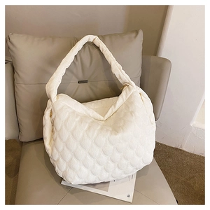 Close-up of white quilted corduroy tote bag showing soft shell texture and wide strap