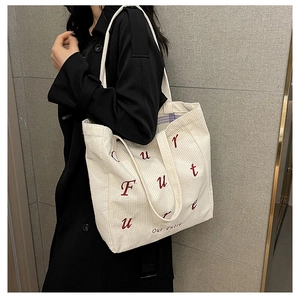 Detail of white corduroy tote bag with red Future embroidery and purple plaid lining