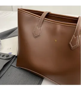 Détail d'un grand sac cabas marron montrant le cuir lisse et les coutures contrastées