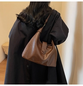Detail of vintage dark brown leather tote bag with round buckle on a model