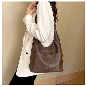 Détail du sac hobo en cuir marron avec poche avant et texture cuir ciré lisse