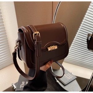 Detailed view of vintage dark brown leather saddle bag with wave flap and gold buckle