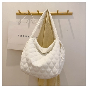 Detailed view of white quilted tote bag with wavy texture hanging on a wooden hook
