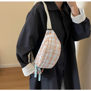 Detail of blue and orange checkered corduroy crossbody bag with woven tassel accent