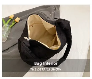 Interior view of black quilted tote bag showing smooth beige lining and zipper pocket