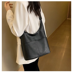 Détail du sac à épaule en cuir noir avec deux poches avant et finition grainée mate