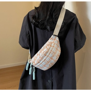 Detail of blue and orange plaid crossbody bag with decorative woven zipper pulls