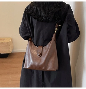 Detail view of the brown leather shoulder bag with sleek strap and elegant metallic buckle