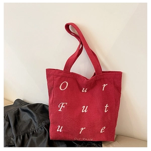 Close-up of red corduroy tote bag featuring white Our Future embroidered lettering