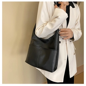 Détail du sac cabas noir en cuir avec poche porté sur un blazer blanc élégant
