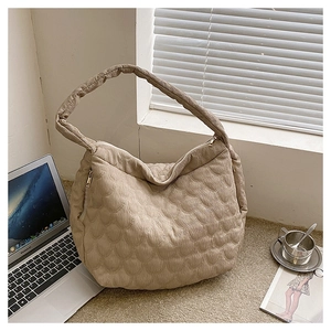 Detailed view of quilted beige canvas tote bag with thick shoulder strap and side zipper pocket