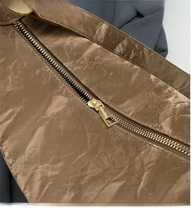 Détail de la fermeture éclair dorée et de la texture plissée marron sur le sac à main