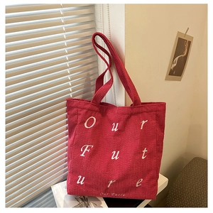 Close-up of red corduroy tote bag with white Our Future embroidery by the window