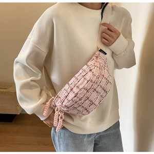 Close-up of pink and white tweed crossbody bag with woven zipper and canvas strap