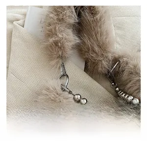 Détail du crochet en métal argenté et de la chaîne perlée sur un sac en fausse fourrure