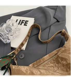 Détail de la texture plissée en similicuir marron avec pendentif feuille sur le sac à main