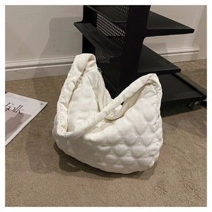 Detail of white quilted tote bag featuring embossed corduroy texture on grey carpet